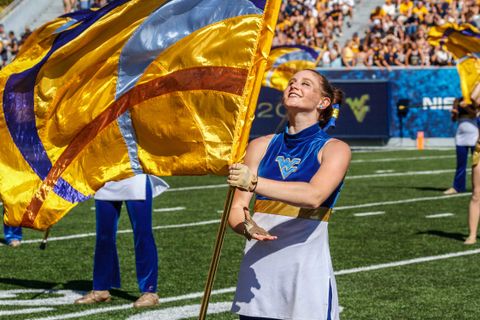 girl twirling a flag and smiling on the field