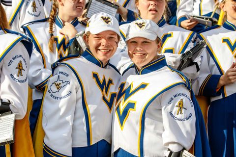 two female band members in uniform smiling for the camera